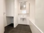 Badezimmer mit Toilette, Badewanne & Waschmaschinenanschluss - Erstbezug! 2‑Zimmer Gartenwohnung mit Garagenplatz und Gemeinschaftsdachterrasse